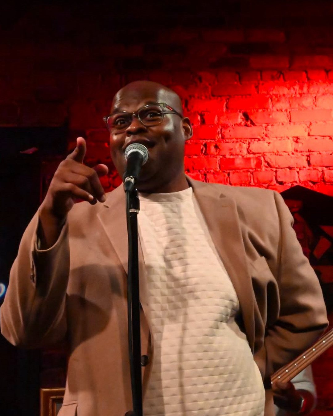 Quentin Talley performing at the microphone under red stage light.