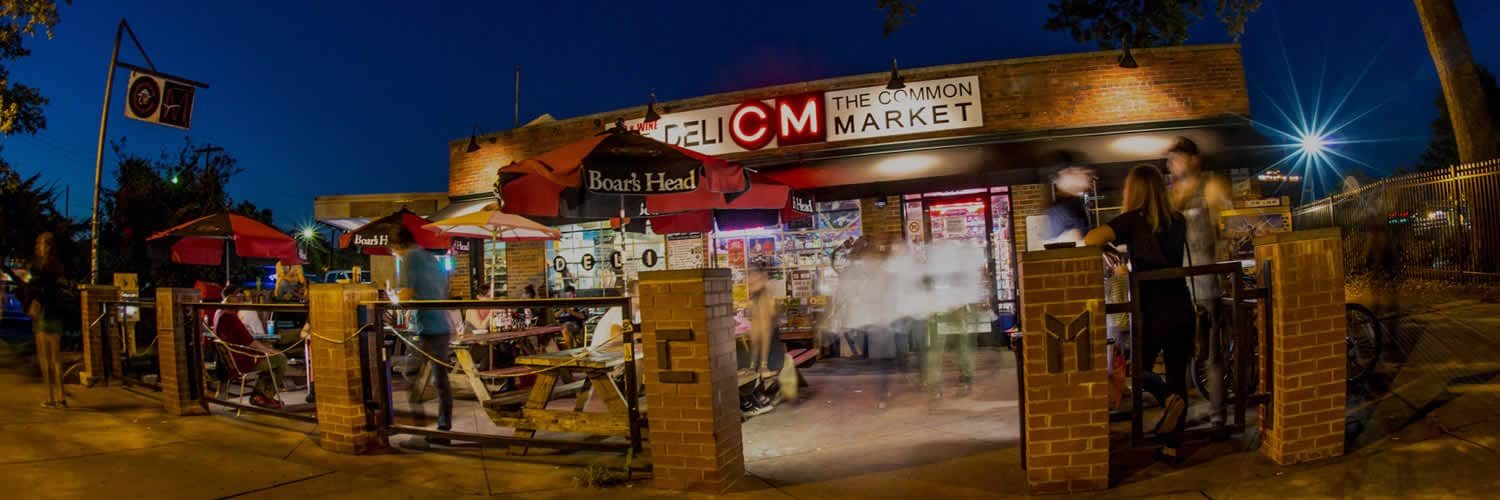 The Common Market Plaza Midwood at dusk, its sign lit over the patio.