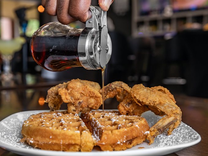 Syrup poured over fried chicken and waffles at Mr. Charles.