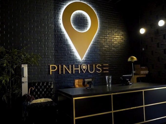 The illuminated Pinhouse sign on a black brick wall.